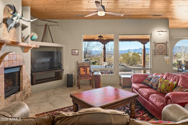 living room featuring a fireplace, light tile patterned floors, ceiling fan, and wood ceiling