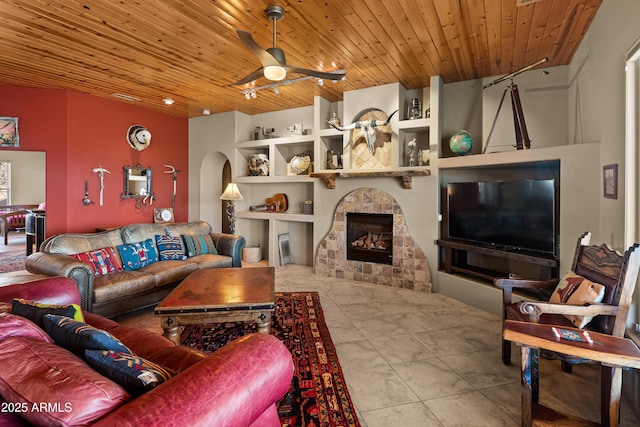 living room featuring wooden ceiling, ceiling fan, a tiled fireplace, light tile patterned flooring, and built in features