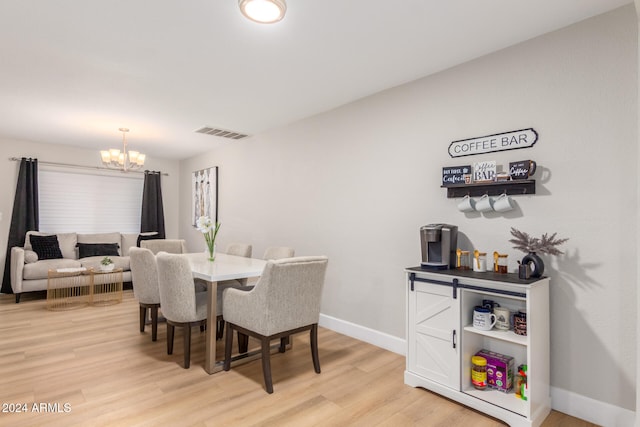 dining area with light hardwood / wood-style flooring and an inviting chandelier