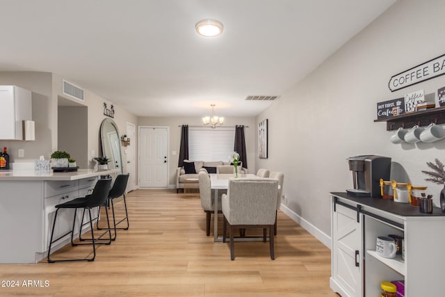 dining space with light hardwood / wood-style floors and an inviting chandelier