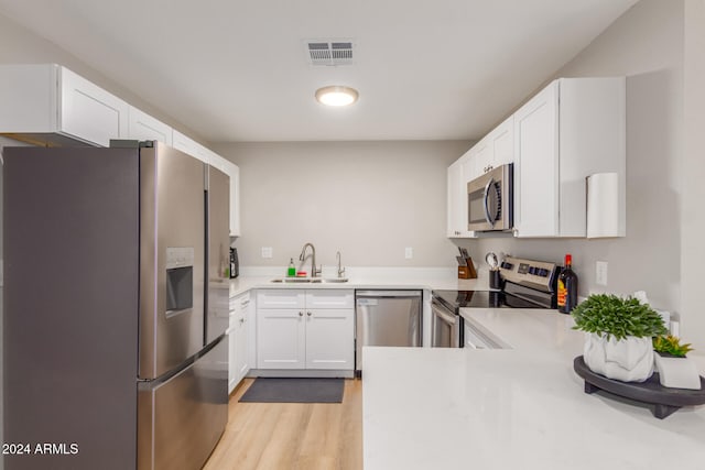 kitchen featuring white cabinets, sink, light hardwood / wood-style flooring, kitchen peninsula, and stainless steel appliances