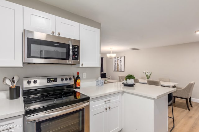 kitchen with kitchen peninsula, appliances with stainless steel finishes, and white cabinetry