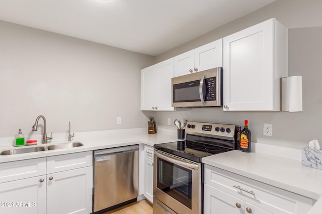 kitchen with white cabinetry, sink, stainless steel appliances, and light hardwood / wood-style flooring