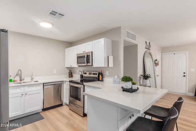 kitchen featuring kitchen peninsula, stainless steel appliances, light hardwood / wood-style floors, and sink