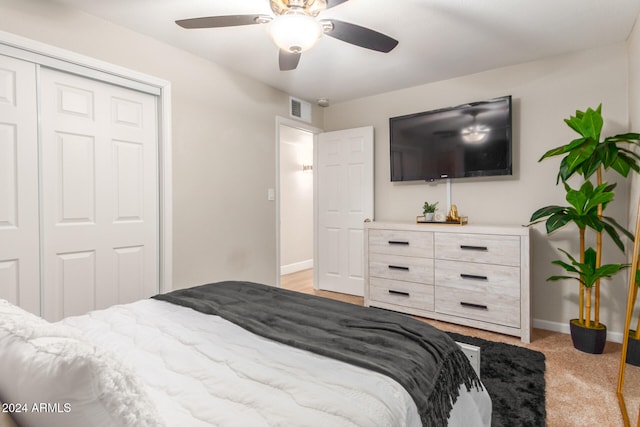 bedroom featuring ceiling fan, light colored carpet, and a closet