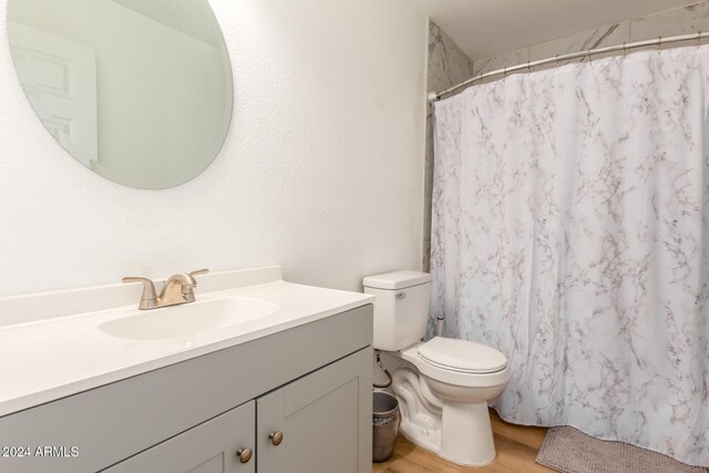 bathroom featuring hardwood / wood-style flooring, vanity, toilet, and walk in shower