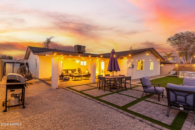 patio terrace at dusk with an outdoor hangout area, central AC unit, and grilling area