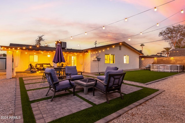 patio terrace at dusk featuring a yard and an outdoor living space