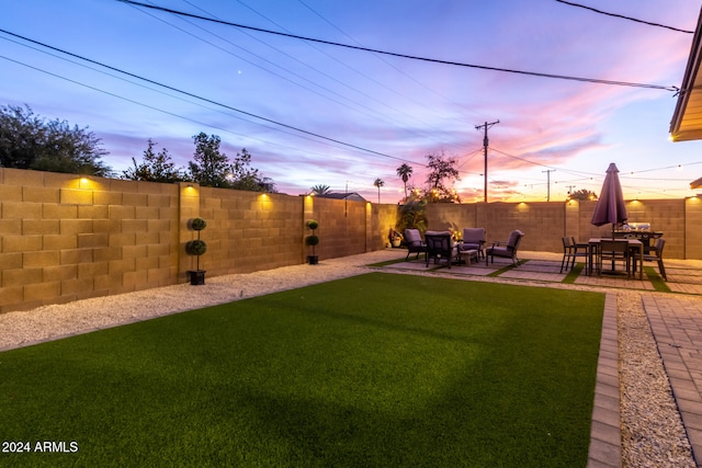 yard at dusk featuring a patio