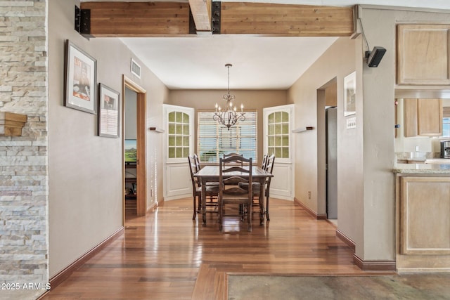 dining space with a chandelier, wood finished floors, visible vents, baseboards, and beamed ceiling