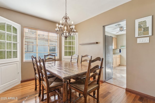 dining area featuring baseboards, visible vents, light wood finished floors, and ceiling fan with notable chandelier