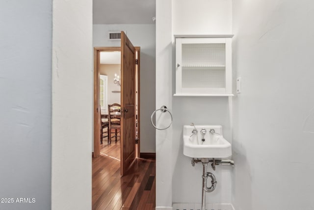 bathroom featuring hardwood / wood-style floors, visible vents, and baseboards