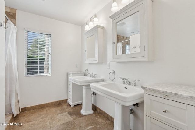 full bathroom with two sinks and baseboards