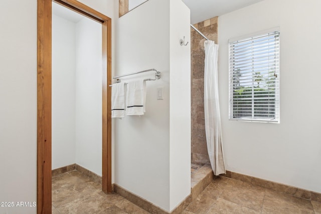 full bath with a tile shower and baseboards