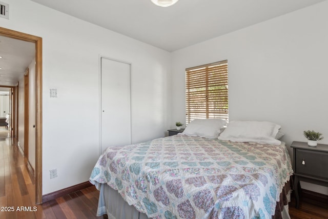 bedroom with baseboards, visible vents, and wood finished floors