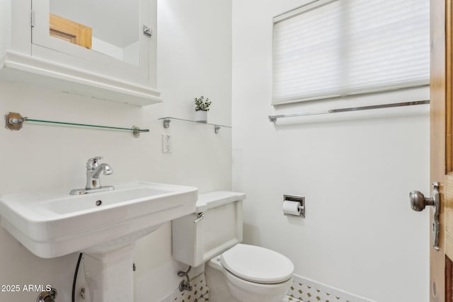 bathroom featuring toilet, baseboards, and a sink