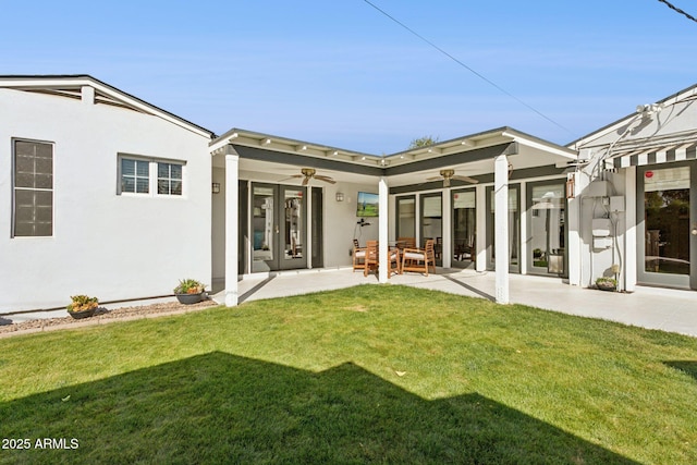 rear view of property with ceiling fan, a lawn, a patio area, and stucco siding