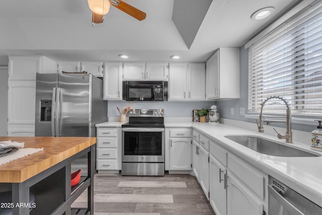 kitchen featuring stainless steel appliances, butcher block counters, light wood-style flooring, white cabinetry, and a sink