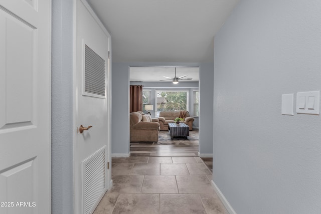 hallway featuring visible vents, baseboards, and light tile patterned flooring