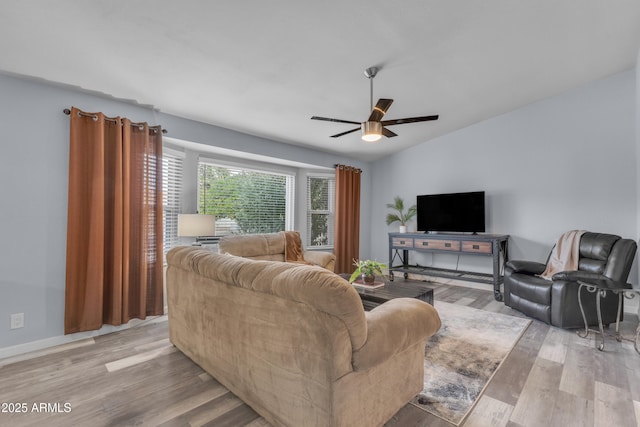 living area with light wood-style flooring, baseboards, and ceiling fan