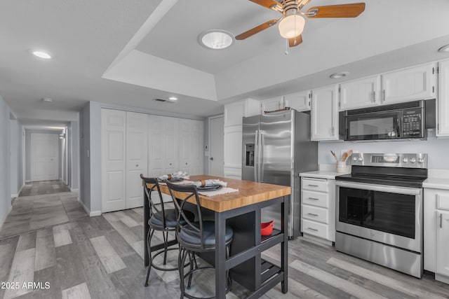 kitchen featuring stainless steel appliances, light countertops, white cabinetry, and light wood-style floors