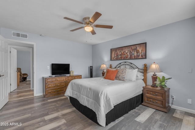 bedroom with visible vents, baseboards, and wood finished floors