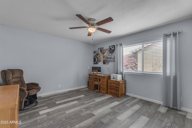 unfurnished office with a ceiling fan, baseboards, and wood finished floors