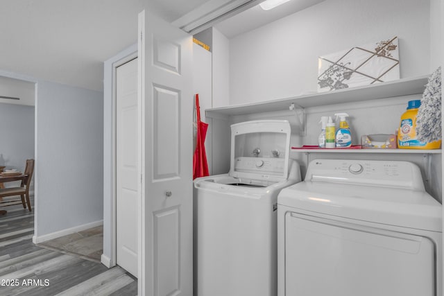 laundry area with laundry area, baseboards, washer and clothes dryer, and wood finished floors