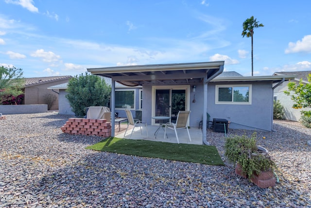 rear view of house with a patio and stucco siding