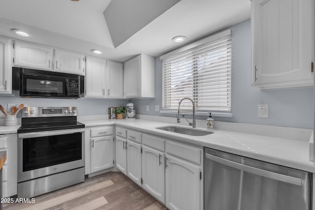 kitchen featuring stainless steel appliances, light countertops, a sink, and white cabinetry