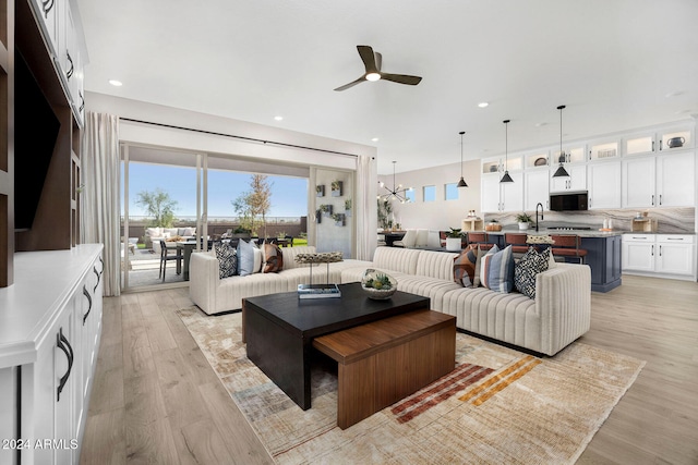 living room with ceiling fan, sink, and light wood-type flooring