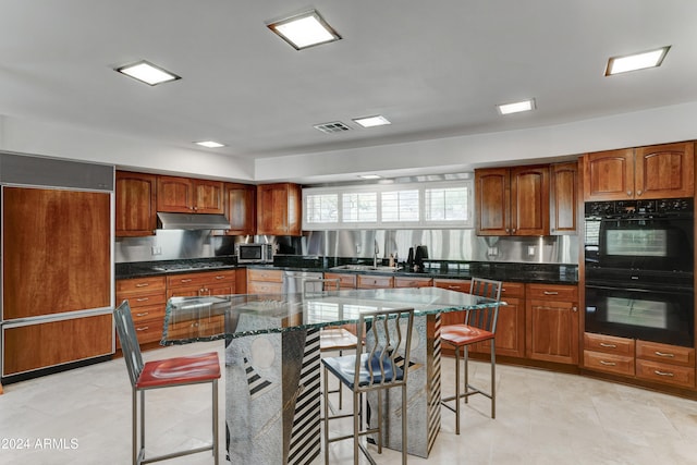 kitchen with a center island, stainless steel appliances, dark stone counters, and a breakfast bar area