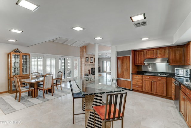 kitchen with a kitchen breakfast bar, dark stone countertops, light tile patterned floors, and appliances with stainless steel finishes