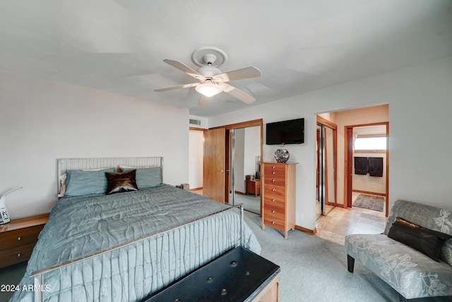 bedroom with connected bathroom, ceiling fan, a closet, and light carpet