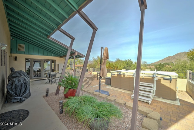 view of patio / terrace with a mountain view, french doors, and a hot tub