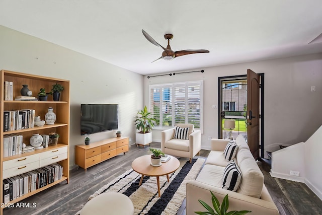 living area featuring ceiling fan, dark wood-style flooring, and baseboards