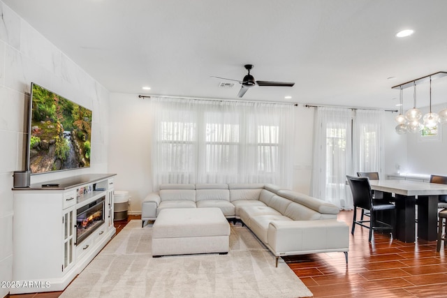 living area featuring ceiling fan with notable chandelier, wood finished floors, visible vents, and recessed lighting