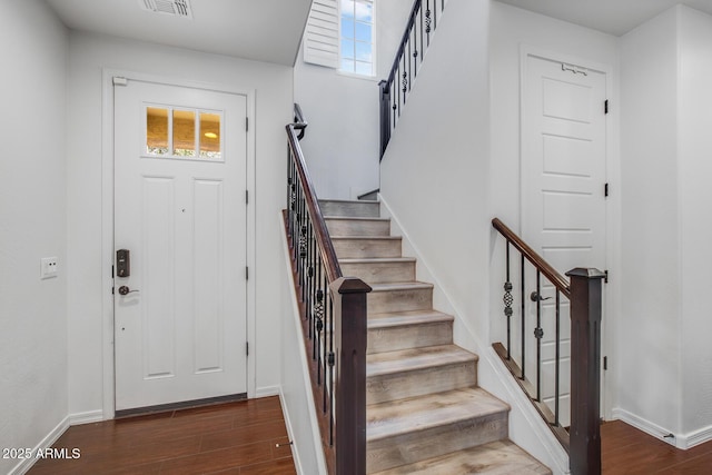 entrance foyer with visible vents, stairs, baseboards, and wood finished floors