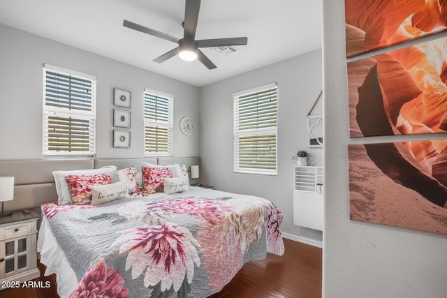 bedroom with ceiling fan, wood finished floors, visible vents, and baseboards