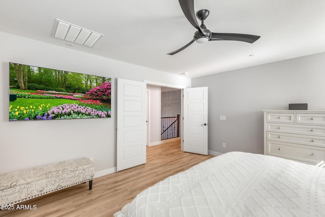 bedroom featuring light wood finished floors, visible vents, baseboards, and a ceiling fan