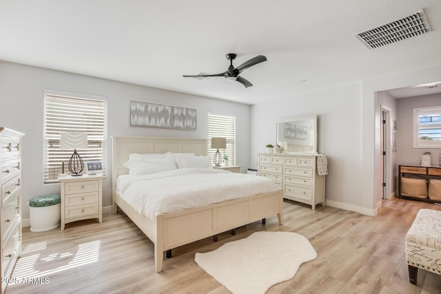 bedroom with visible vents, multiple windows, light wood-style flooring, and baseboards