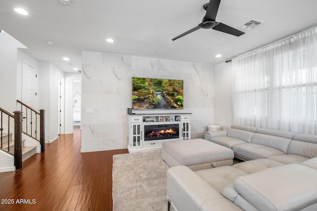 living area with recessed lighting, wood finished floors, visible vents, stairs, and a glass covered fireplace