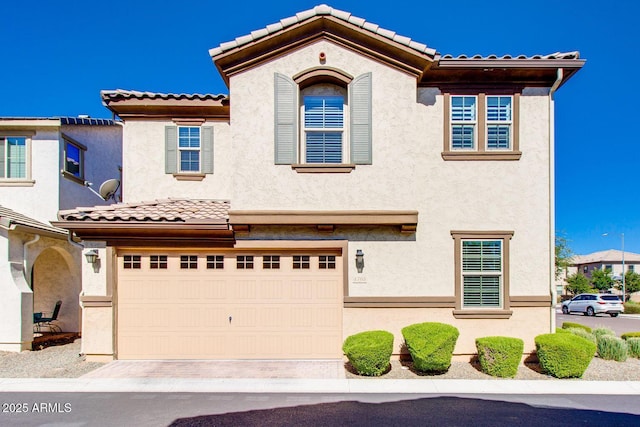 view of front facade featuring an attached garage, a tile roof, and stucco siding