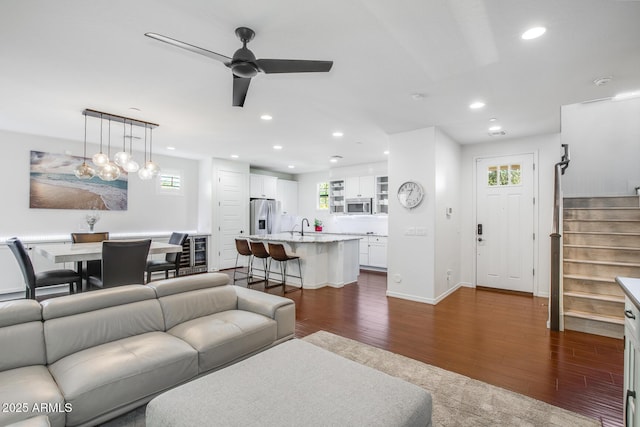 living room featuring baseboards, ceiling fan, stairway, dark wood-style flooring, and recessed lighting