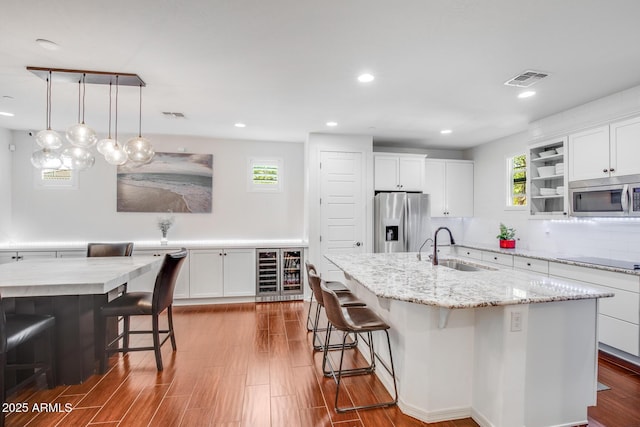 kitchen with appliances with stainless steel finishes, wine cooler, a sink, and a breakfast bar