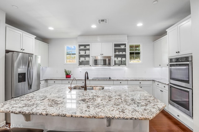 kitchen featuring appliances with stainless steel finishes, a sink, visible vents, and a kitchen breakfast bar