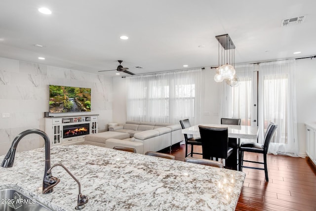 living room with plenty of natural light, visible vents, dark wood finished floors, and a glass covered fireplace