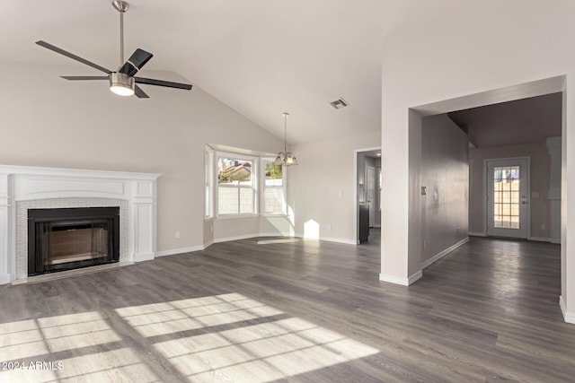 unfurnished living room featuring ceiling fan with notable chandelier, dark hardwood / wood-style flooring, and a tiled fireplace