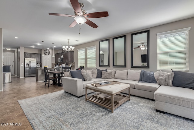 living room featuring ceiling fan with notable chandelier and plenty of natural light