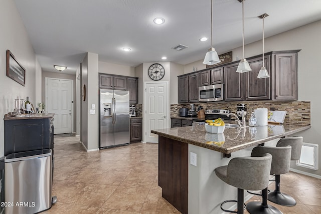 kitchen featuring dark stone countertops, tasteful backsplash, stainless steel appliances, and dark brown cabinets